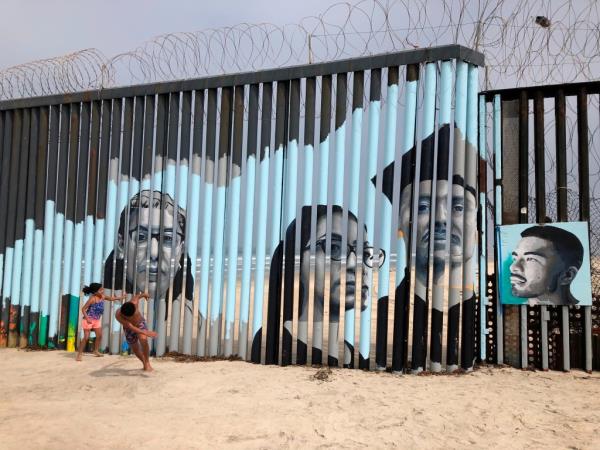 Children play in front of a mural by artist Lizbeth De La Cruz Santana, on the Mexican side of a border wall in Tijuana, Mexico Aug. 9, 2019.