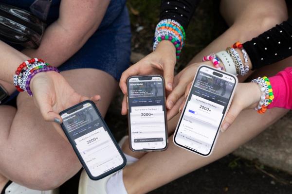 (From left) Anna Mason, Emily Lind, and Kristen Robinson show their Ticketmaster queue, which displays over 2000+ people ahead of them, from the parking lot outside of the Taylor Swift co<em></em>ncert at Lincoln Financial Field in Philadelphia, Pennsylvania on May 13, 2023