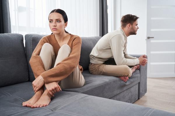 Young man and woman sitting on a sofa facing opposite directions