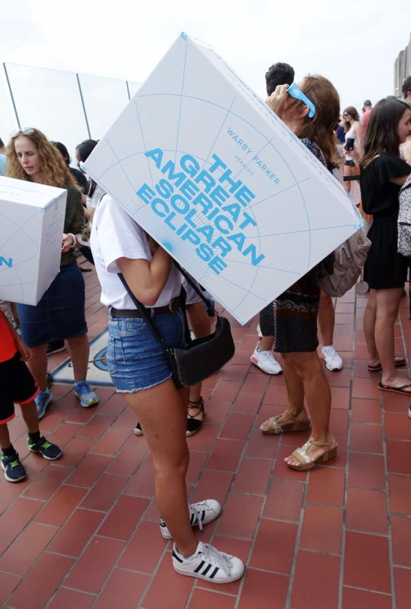 Ginerva D'Amiano, 18, of Milan, uses a pinhole projector box to view a solar eclipse in this view from Top of the Rock Monday, Aug. 21, 2017