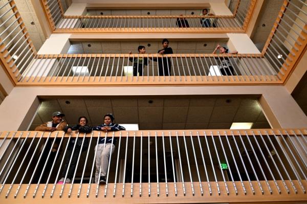 Migrants looking down from balco<em></em>nies at a Denver shelter.