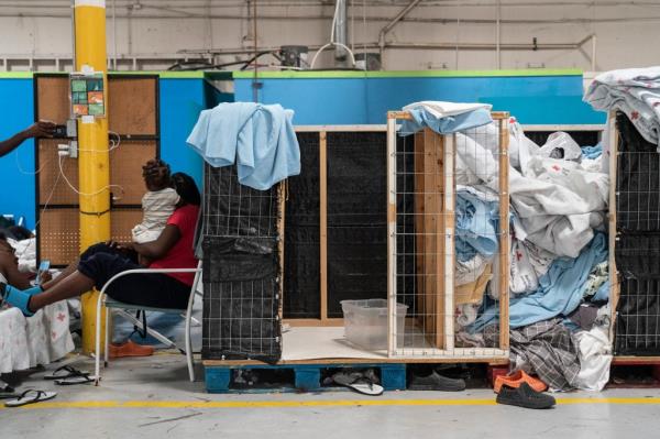 woman with baby, facing away from camera, surrounded by laundry 