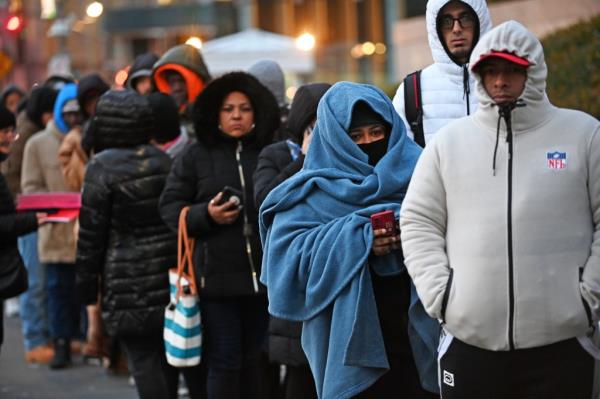 Newly arrived migrants queue outside immigration building in Manhattan, some with children, in the dark. (Credit Image: Andrea Renault/ZUMA Press Wire)