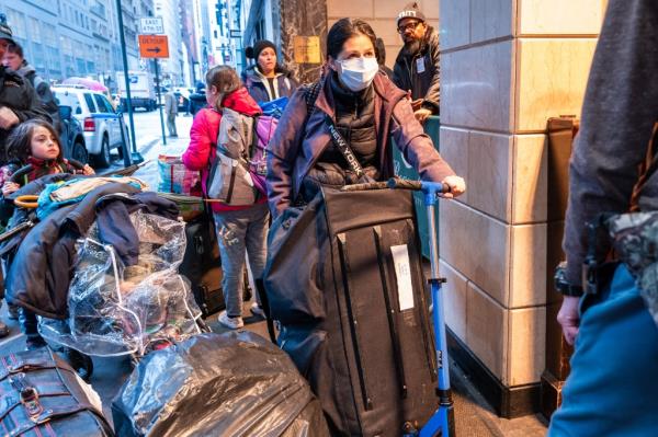 A group of migrants and their belo<em></em>ngings on a sidewalk in New York City.