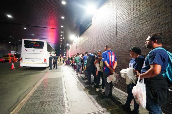 a line of migrants in the bus tation 