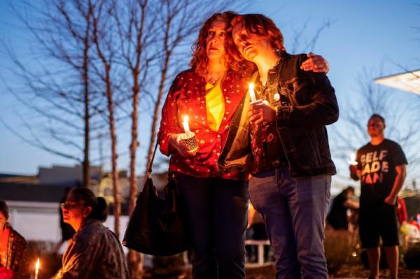 Two people participate in a community candlelight vigil for Nex Benedict