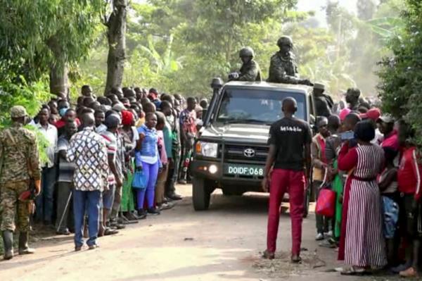 security forces drive past a crowd of people gathered outside the Lhubiriha Seco<em></em>ndary School following an attack on the school near the border with Congo, in Mpondwe, Uganda, Saturday, June 17, 2023. 