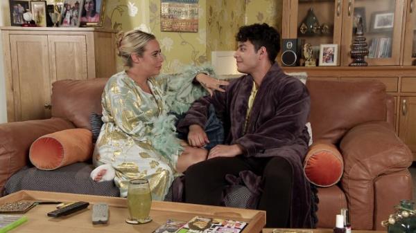 Courtney and Aadi sitting on a sofa in Corrie