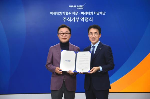 Mirae Asset Financial Group Chairman Park Hyeon-joo (left) poses for a photo after pledging to do<em></em>nate 25 percent of his stake in Mirae Asset Co<em></em>nsulting to the Mirae Asset Hope Foundation at the Mirae Asset Center One in central Seoul, Dec. 26. (Mirae Asset Financial Group)