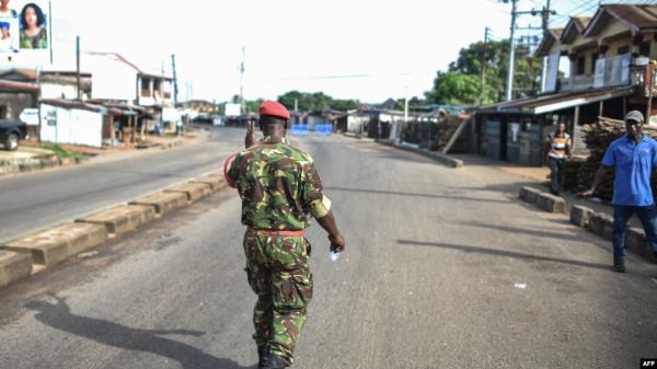 A soldier with the Sierra Leo<em></em>nean military police greets and man along an empty road in Freetown, Nov. 26, 2023.